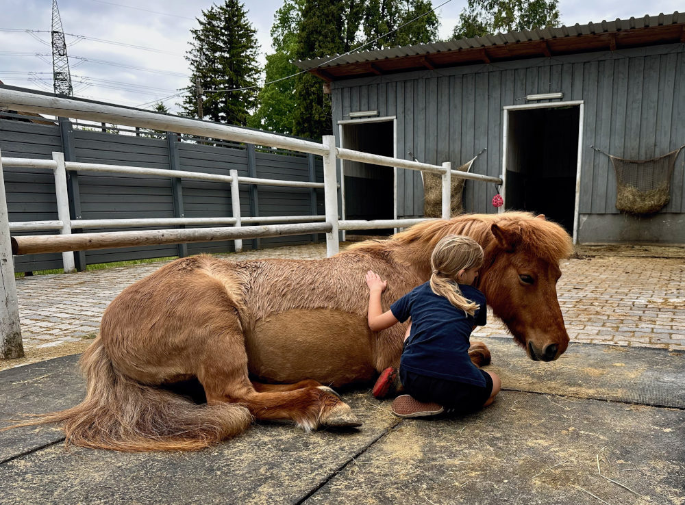 Ylvi liegt tiefenentspannt am Boden, Kind kuschelt sich an